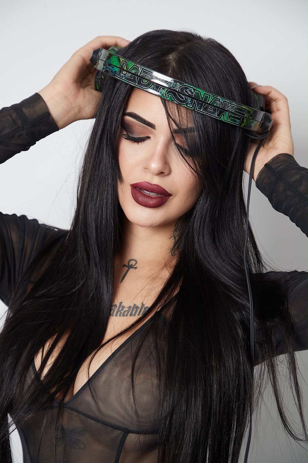 Lady Snake holding her headphones with the snake logo
